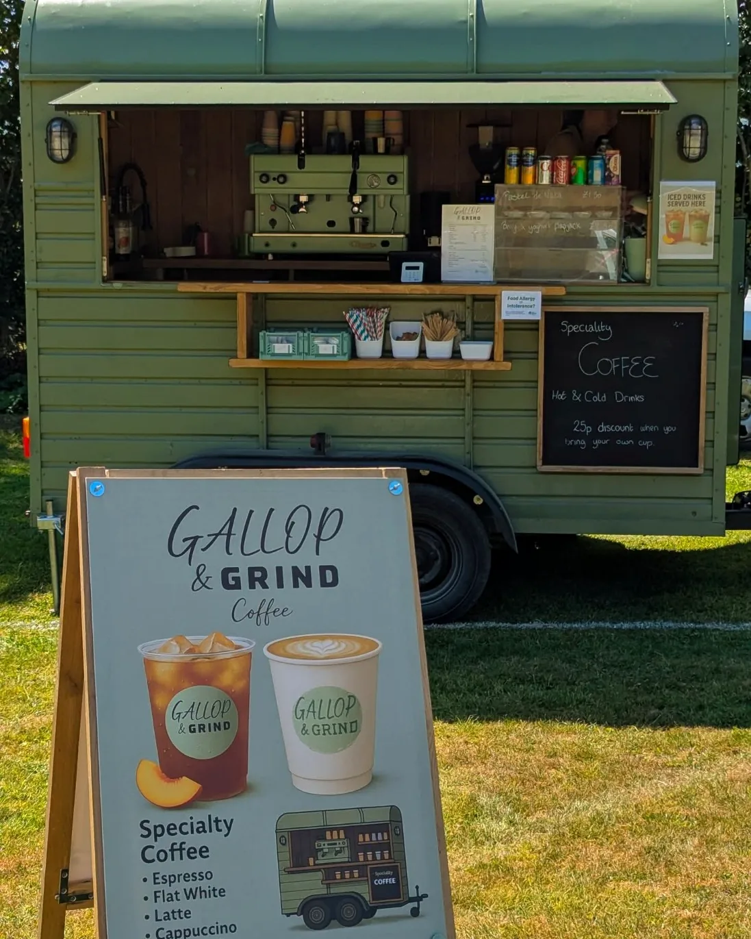 The Gallop & Grind horsebox pitched on grass, hatch open, with a branded speciality coffee menu board in front