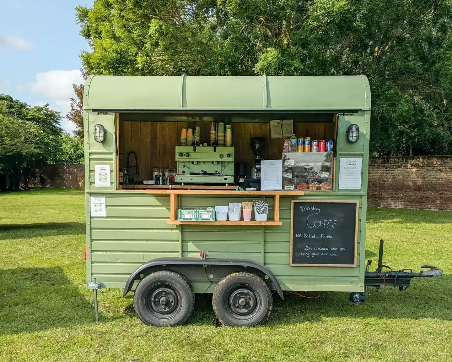 The sage-green Gallop & Grind horsebox open for service on grass, with the restored Astoria lever espresso machine inside