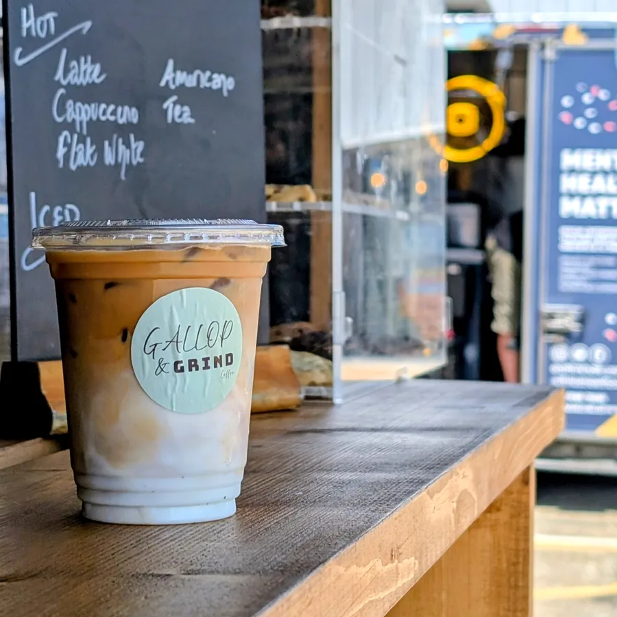 An iced latte in a Gallop & Grind branded cup on the serving hatch